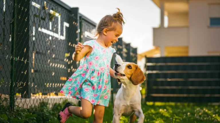 Barn leker med hund i trädgården.
